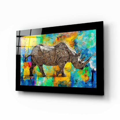 Framed glass wall art displaying a detailed gray rhinoceros against a vibrant multicolored abstract background of blues, yellows, greens, and oranges.
