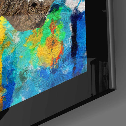 Angled side view of a glass wall art panel displaying a colorful rhinoceros head with vibrant blue, green, yellow, and orange brushstroke patterns.
