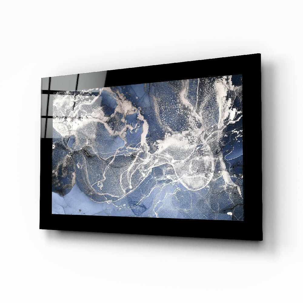 Black-framed blue quartz glass wall art mounted on white wall, displaying satellite or aerial map view with white cloud patterns and blue water.