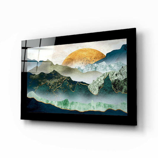 Black-framed glass wall art displaying layered mountains in teal, green, and gold with a golden sun, mounted at an angle.