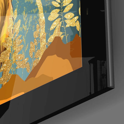 Close-up angled view of glass wall art showing golden glitter foliage on teal background with layered orange and brown mountain silhouettes.