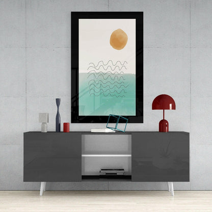 Framed minimalist seascape artwork with golden sun and turquoise waves displayed on gray media console with red lamp and accessories.