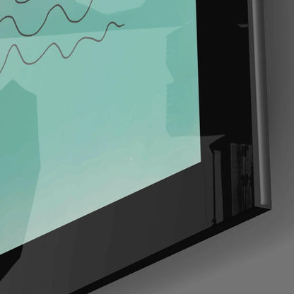 Angled side view of framed turquoise glass wall art with wavy line design displayed on gray surface.