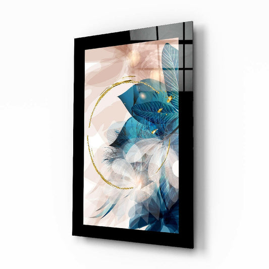 Black-framed glass wall art displaying abstract blue and teal feathers with gold circular accent, angled perspective view.