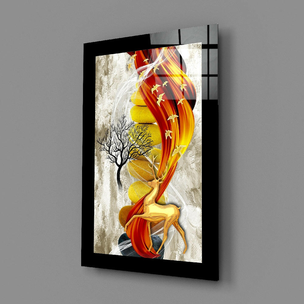 Black-framed glass wall art displaying red and gold deer with flowing ribbons and bare tree, angled perspective view.