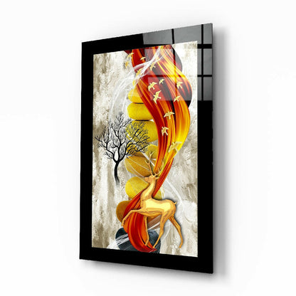 Framed glass wall art featuring a golden deer with red flowing fabric and bare tree, displayed at an angle showing the black frame and glass surface.