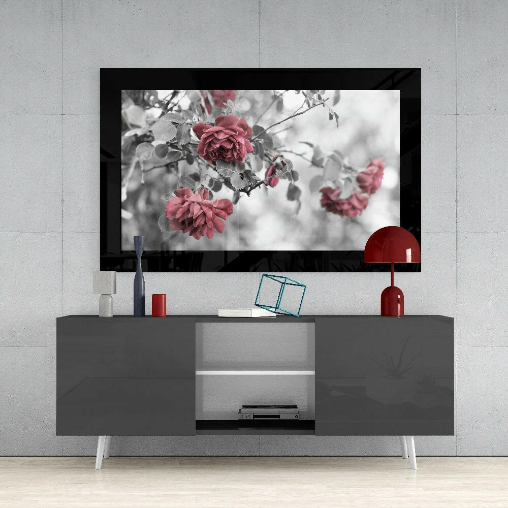 Rosewood glass wall art displaying red roses with selective color against grayscale foliage, mounted above gray media console.