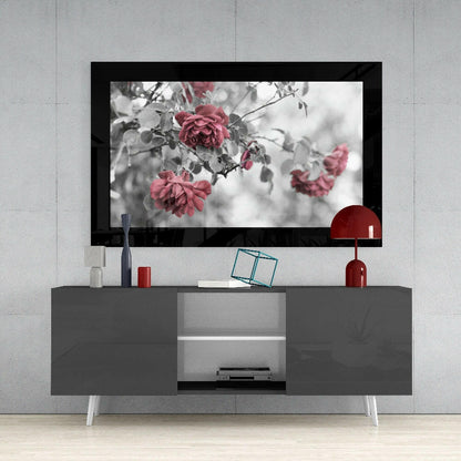 Rosewood glass wall art displaying red roses with selective color against grayscale foliage, mounted above gray media console.