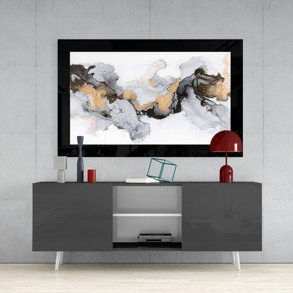 Framed abstract marble glass wall art in gold, gray, and black tones displayed above a gray media console with white legs and decorative accessories.