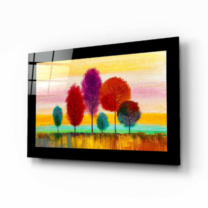 Framed glass wall art displaying colorful stylized trees against a sunset sky in warm yellows, reds, purples, and greens.