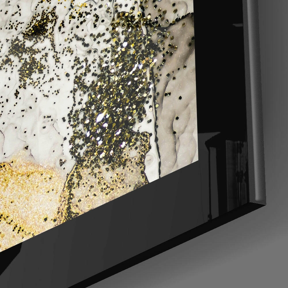 Close-up angled view of gold powder graphite glass wall art showing gold leaf and black speckled texture against white and gray background in black frame.