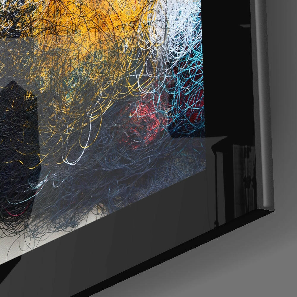 Abstract glass wall art panel with energetic yellow, blue, and red scribbled lines on dark background, displayed at an angle.