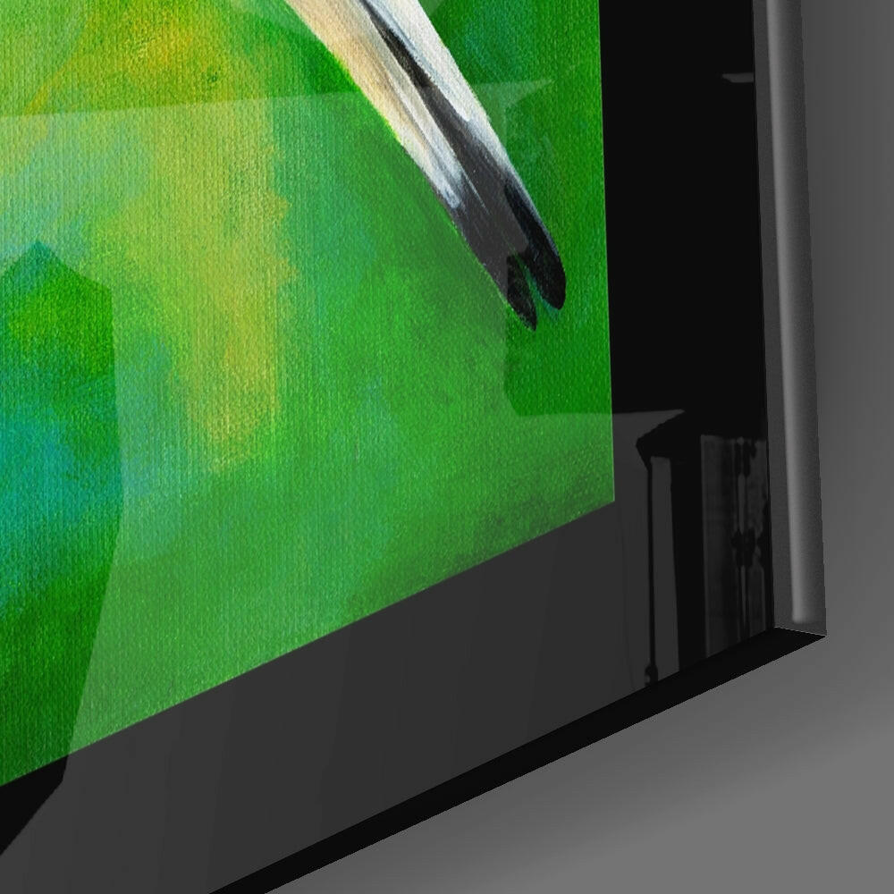 Close-up angled view of glass wall art showing a bird perched on a branch against green and yellow watercolor background.