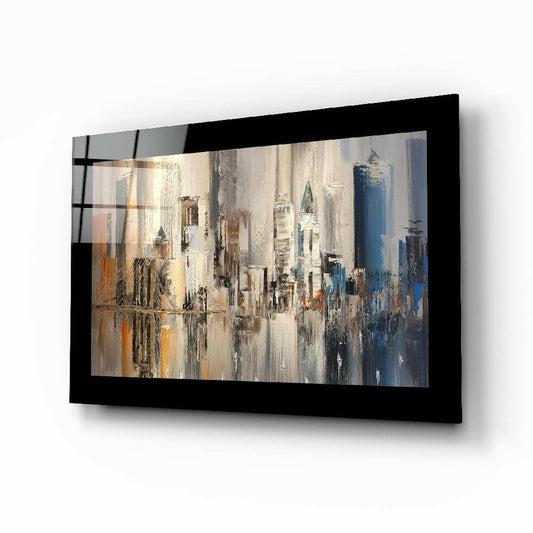 Black-framed glass wall art displaying an abstract cityscape with cream, gold, and blue palette knife brushstrokes depicting tall buildings, mounted at an angle.