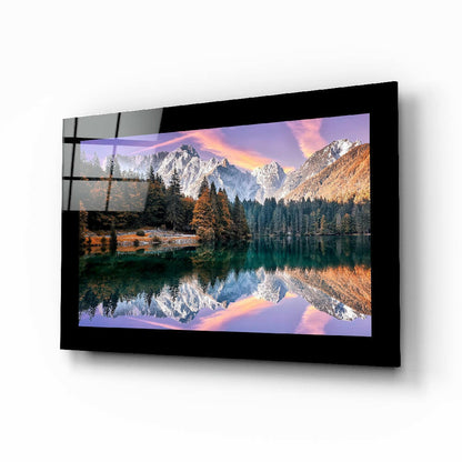 Black-framed glass wall art displaying a mountain lake landscape with snow-peaked peaks, autumn trees, and sunset reflection, mounted at an angle.
