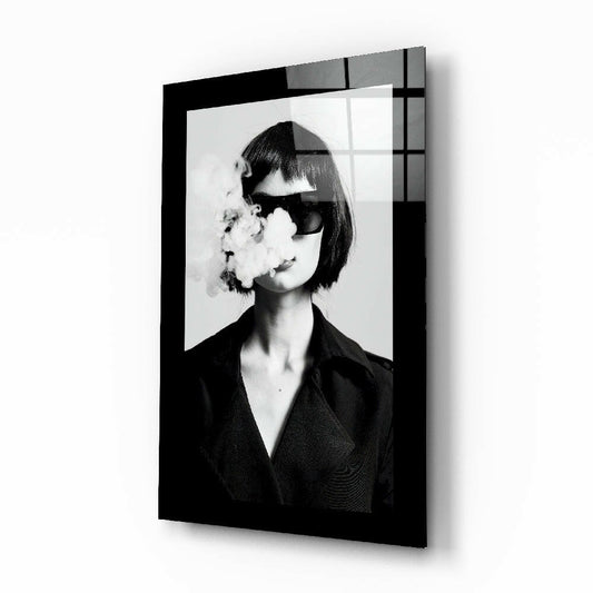 Black and white portrait of woman with bob haircut and dark sunglasses exhaling smoke, mounted on black framed glass wall art displaying geometric grid pattern overlay.