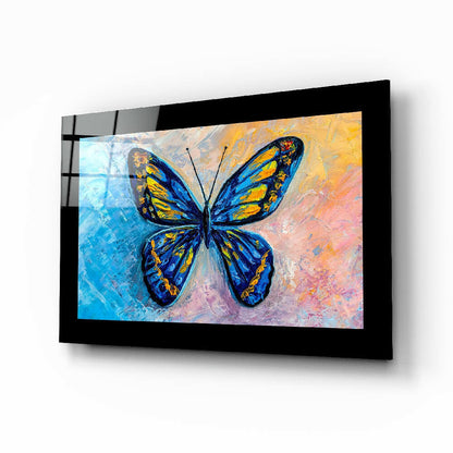 Black-framed glass wall art displaying a vibrant blue and yellow butterfly on colorful gradient background, mounted at angle.