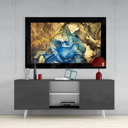 Framed abstract glass wall art with swirling blue and gold tones displayed above a gray media console in a modern living room setting.