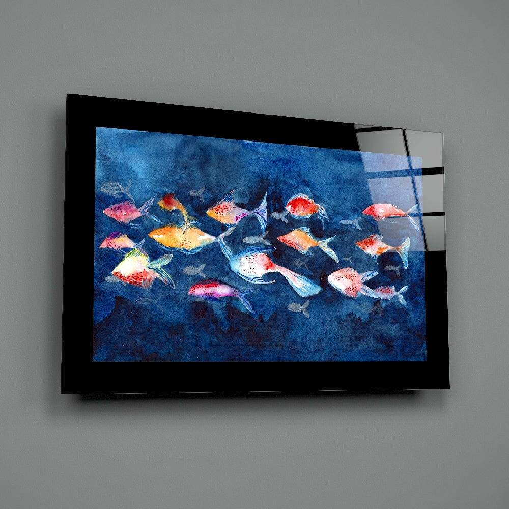 Black-framed glass wall art displaying a school of colorful red, orange, and white fish swimming against a deep blue underwater background.