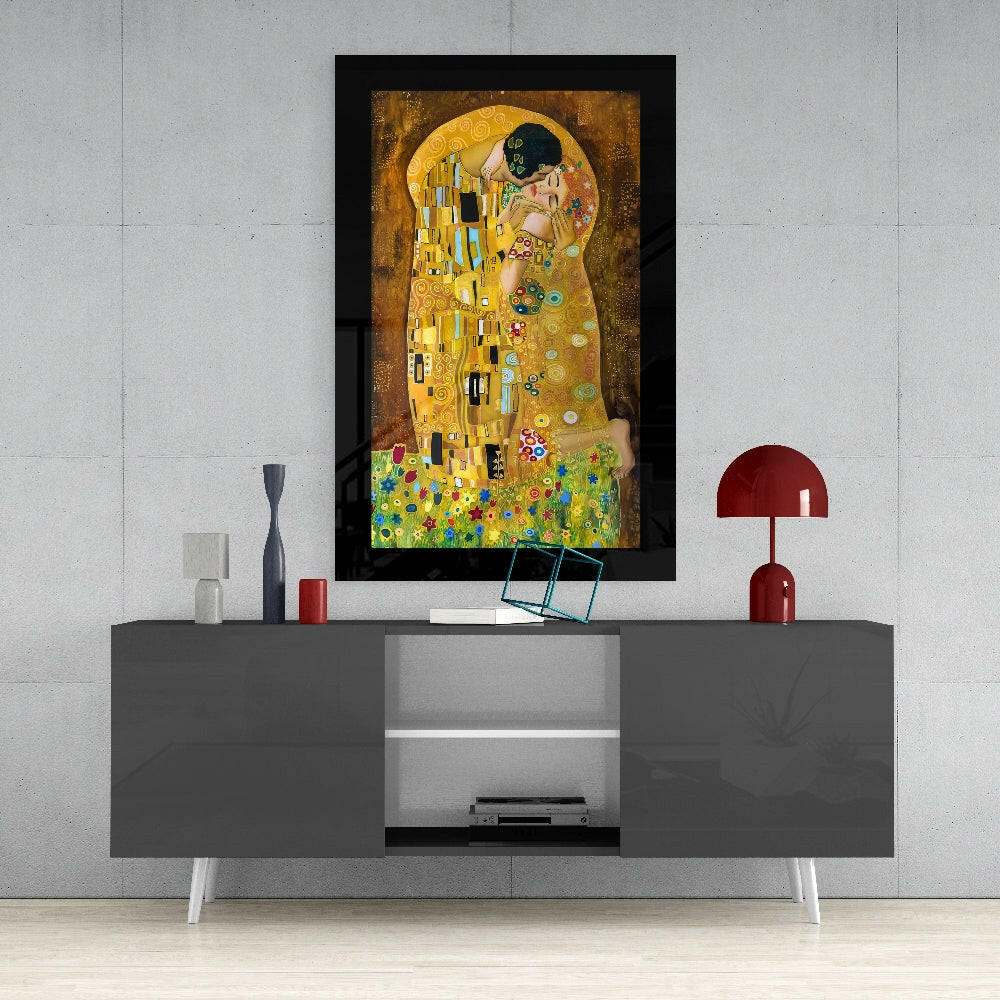 Framed glass art of Klimt's "The Kiss" mounted on a white wall above a gray media console with red decorative accessories.