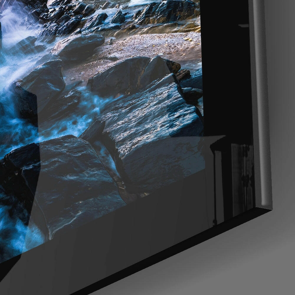Angled side view of framed sea glass wall art displaying rocky coastline with blue water and white foam against dark frame edge.