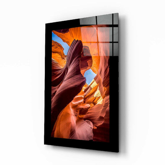 Black-framed glass wall art displaying a landscape photograph of a narrow slot canyon with warm orange and red sandstone walls and blue sky visible above.