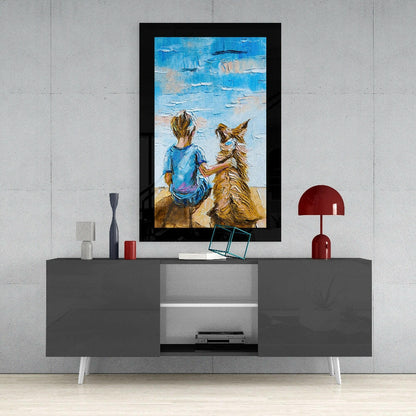 Framed glass wall art depicting a child in blue shirt and dog on beach against blue sky, displayed above gray media console with red lamp and accessories.