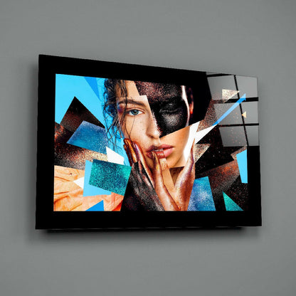 Modern glass wall art featuring a fragmented portrait of a woman's face with blue, orange, and metallic geometric overlays, mounted on gray wall.