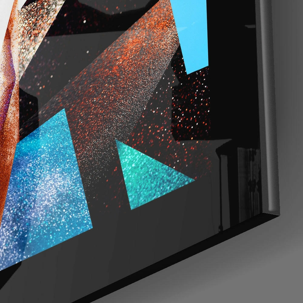 Close-up angled view of modern glass wall art featuring blue and orange glittery triangular shapes on black background.