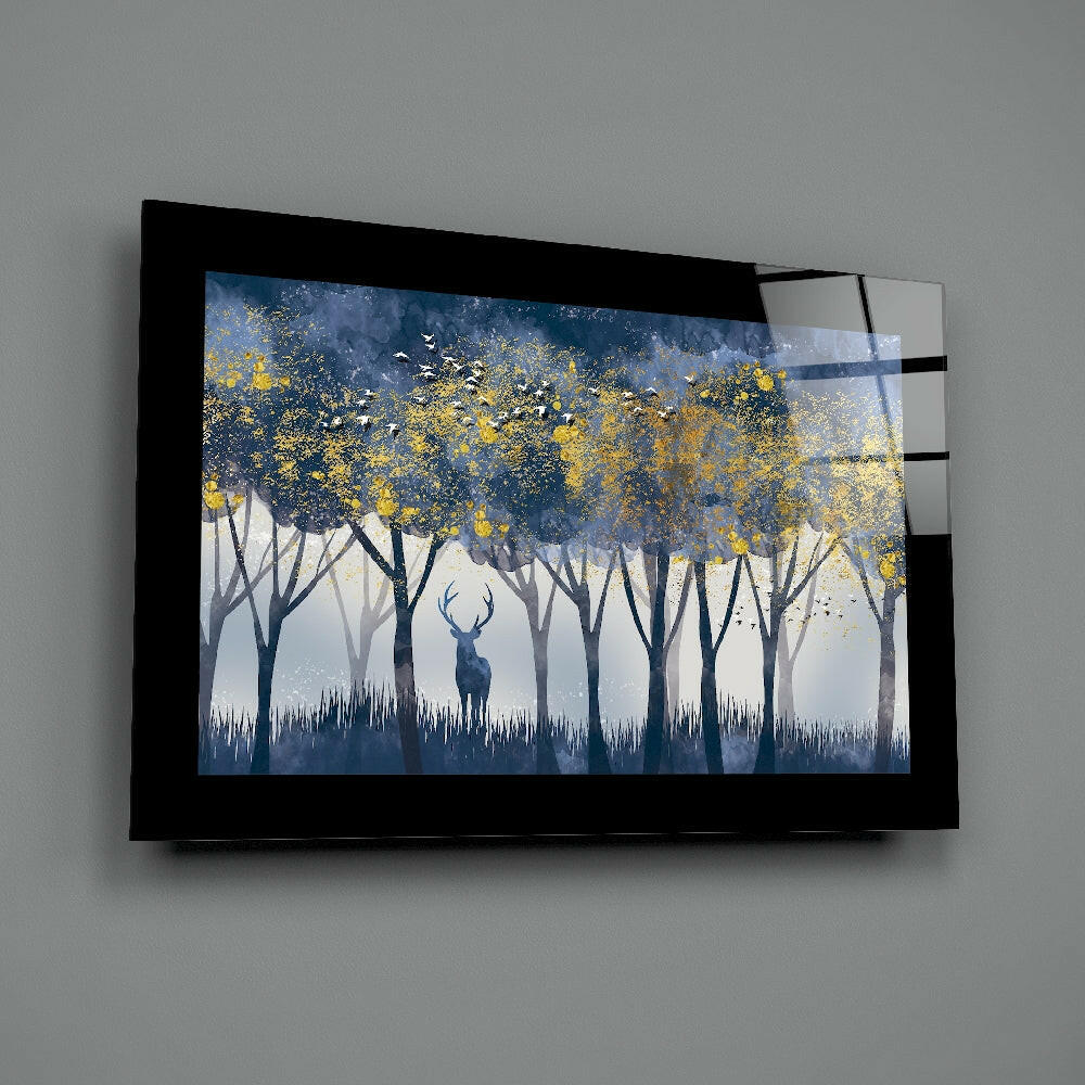 Framed glass wall art displaying a misty forest scene with a silhouetted deer among trees with golden yellow foliage against blue and gray tones.