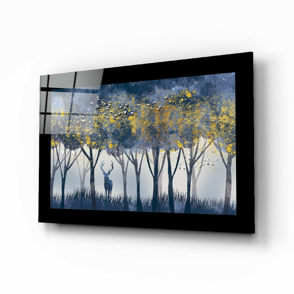 Framed glass wall art displaying a misty forest scene with silhouetted deer and golden yellow foliage, mounted at an angle against white background.
