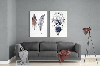 Modern living room with gray sofa displaying two framed glass wall artworks: watercolor feathers and celestial butterfly illustration above.