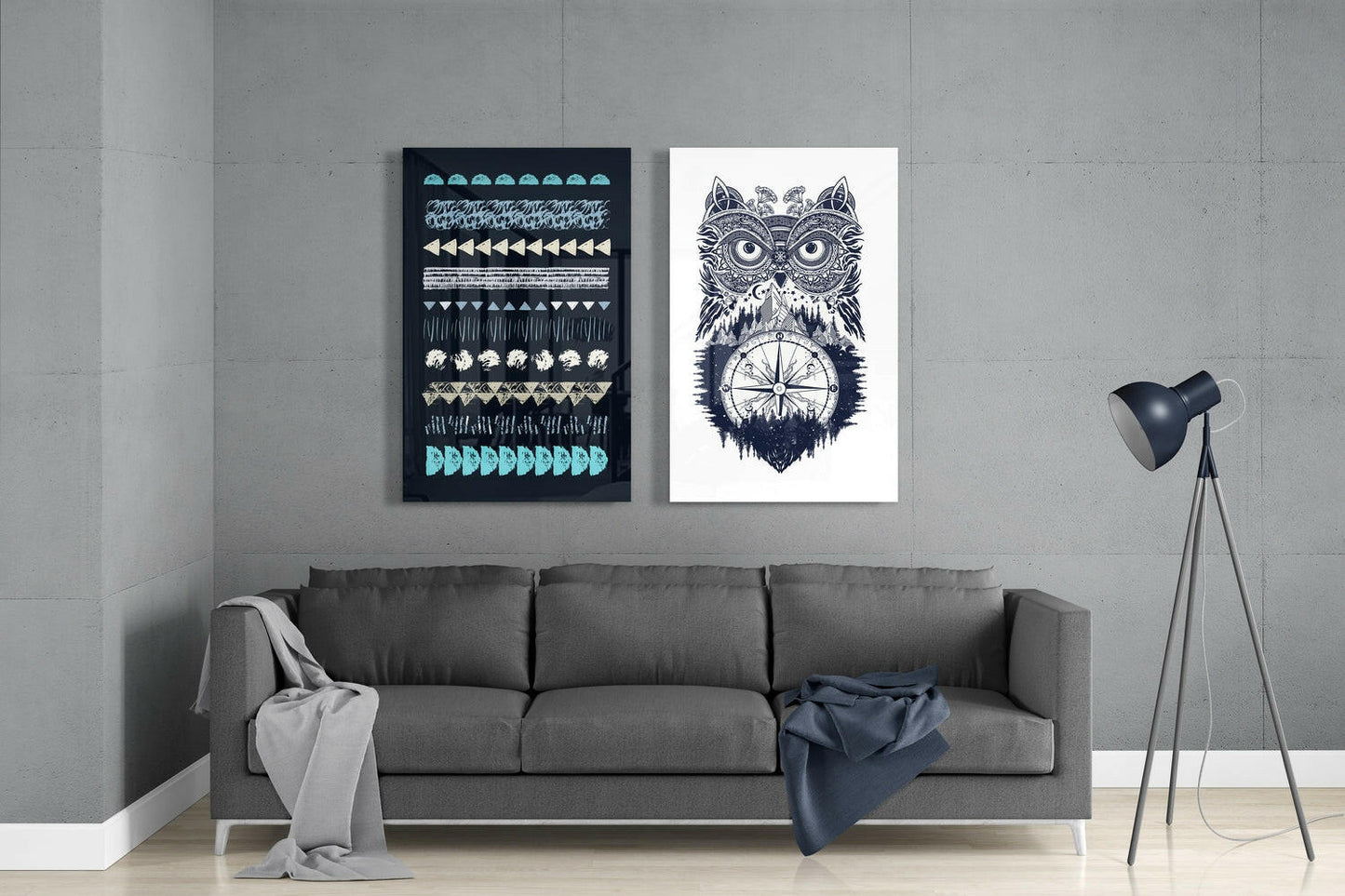 Modern living room with gray sofa displaying two framed glass wall artworks: dark geometric patterns and intricate owl with compass design.