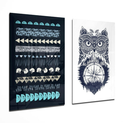 Two glass wall art panels displayed at an angle: left panel with geometric patterns in turquoise, cream, and gray on black; right panel with intricate owl and compass design in navy and white.