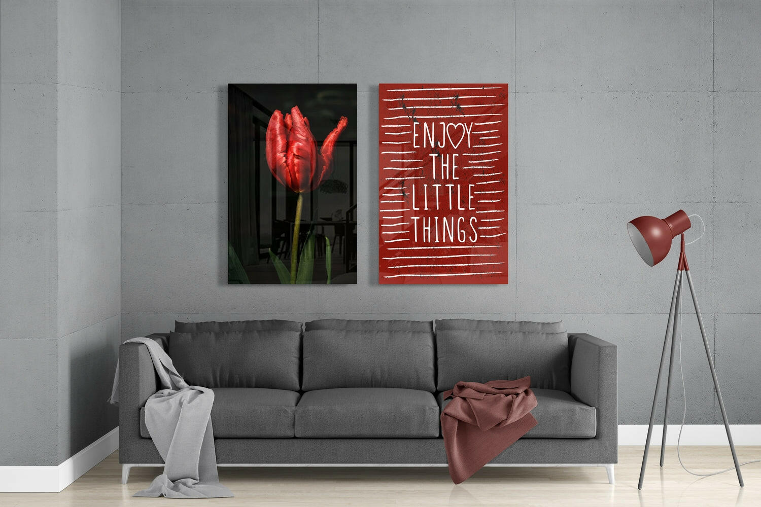 Modern living room display showing red tulip photograph and "Enjoy the Little Things" red glass wall art above gray sofa.