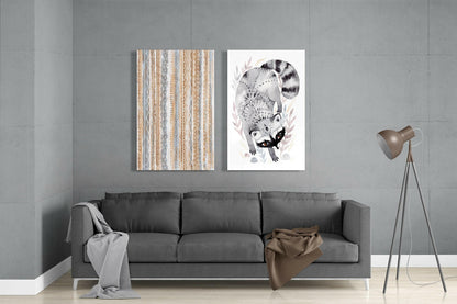 Two framed glass wall art pieces hanging above a gray sofa: left panel shows tan and blue geometric striped pattern; right panel depicts detailed black and white raccoon illustration with foliage.