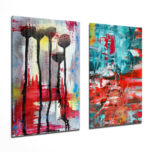 Two abstract glass wall art panels displayed at an angle, featuring stylized flowers with red, turquoise, yellow, and black paint strokes.