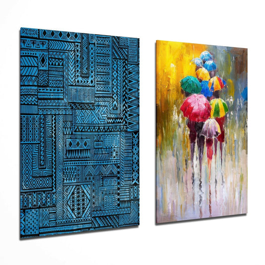 Two glass wall art panels displayed at an angle: left panel features blue and black geometric patterns; right panel shows colorful umbrellas in rain with yellow, red, and blue tones.