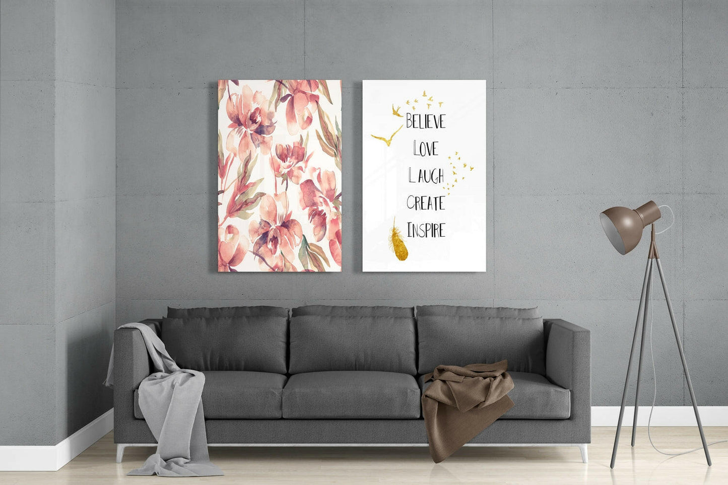 Gray sofa against concrete wall with two framed glass prints: pink floral pattern and motivational text with gold accents.