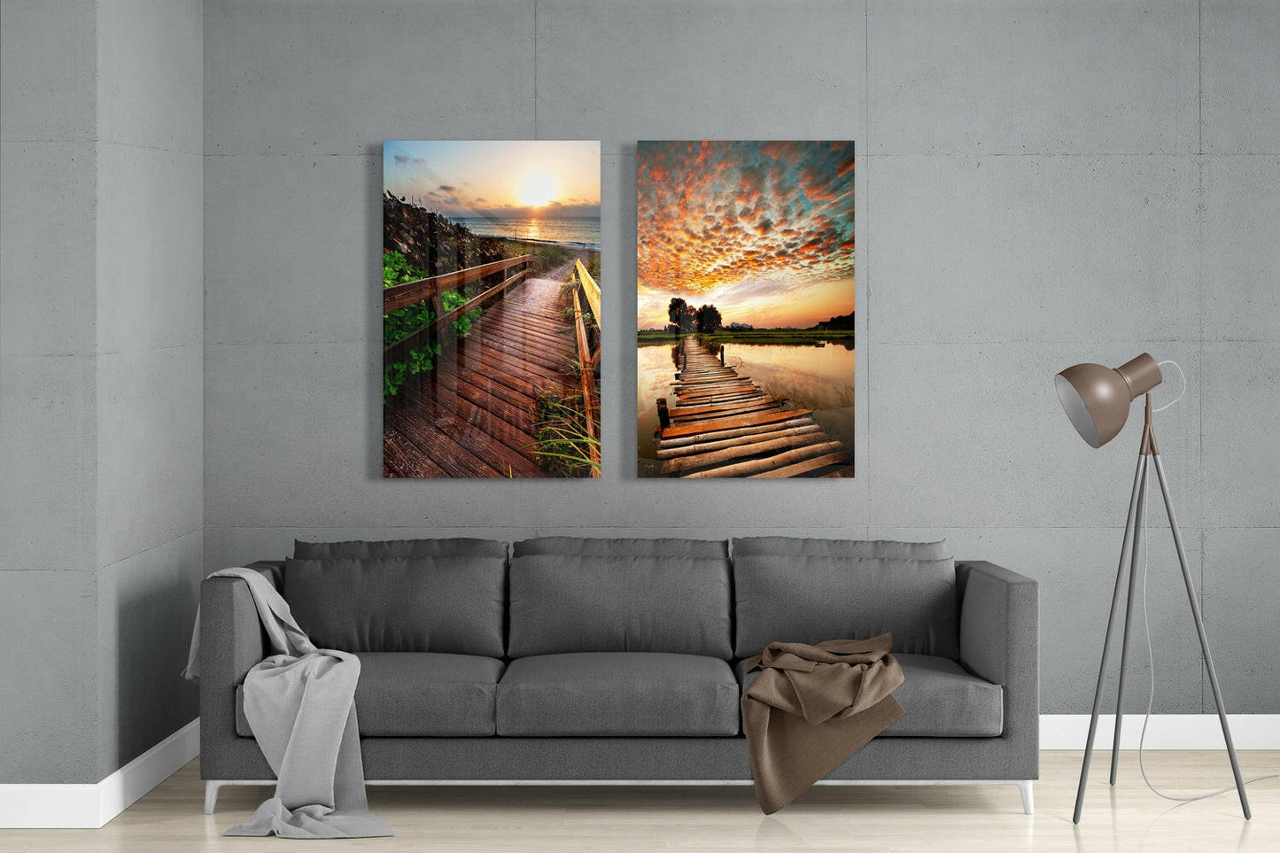 Two glass wall art panels depicting wooden boardwalks at sunset displayed above a gray sofa in a minimalist interior.