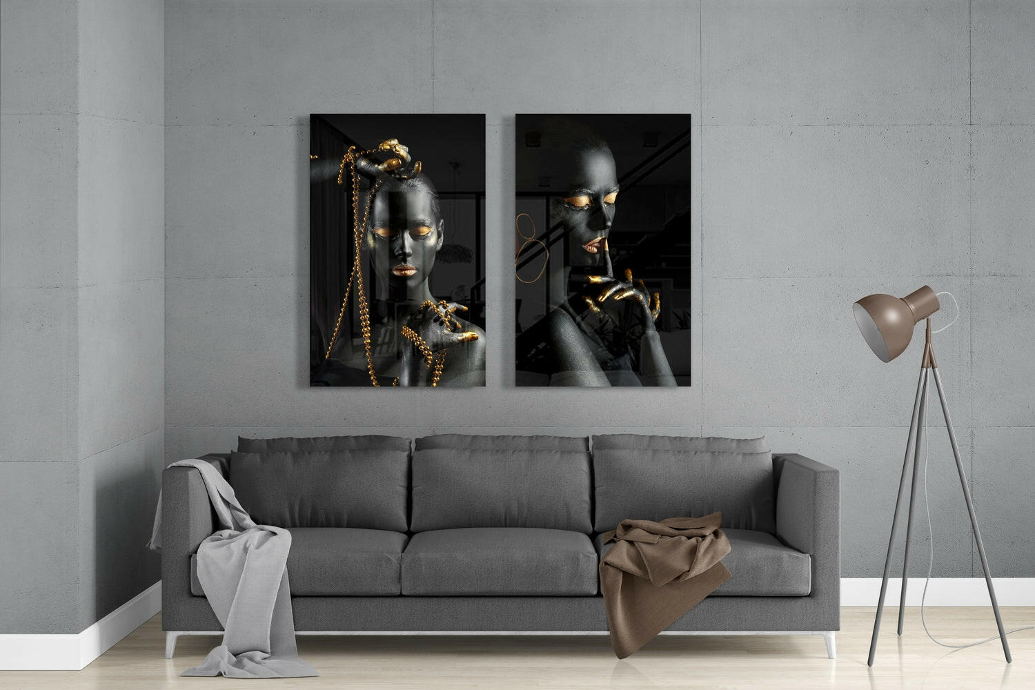 Two black and gold portrait glass panels mounted above gray sofa in minimalist room interior.