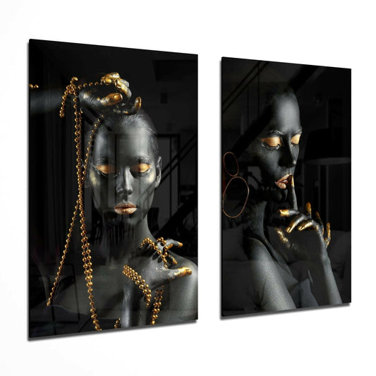 Two glass panels displaying stylized female faces with black skin, gold accents on eyes and lips, gold beaded necklaces, and gold hoop earrings against dark backgrounds.