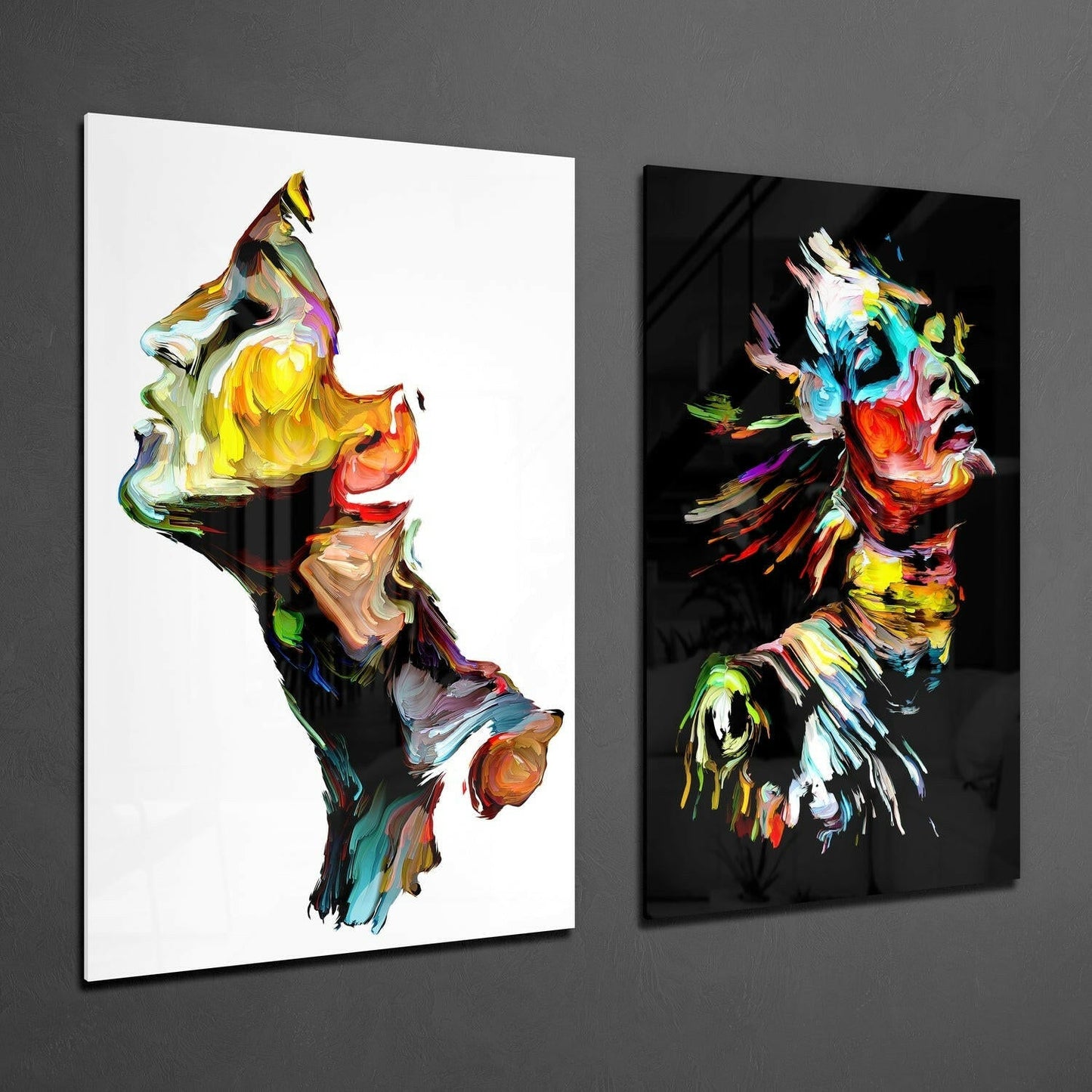 Two colorful abstract glass wall panels mounted on gray wall, left panel white background with vibrant paint strokes, right panel black background with matching artistic design.