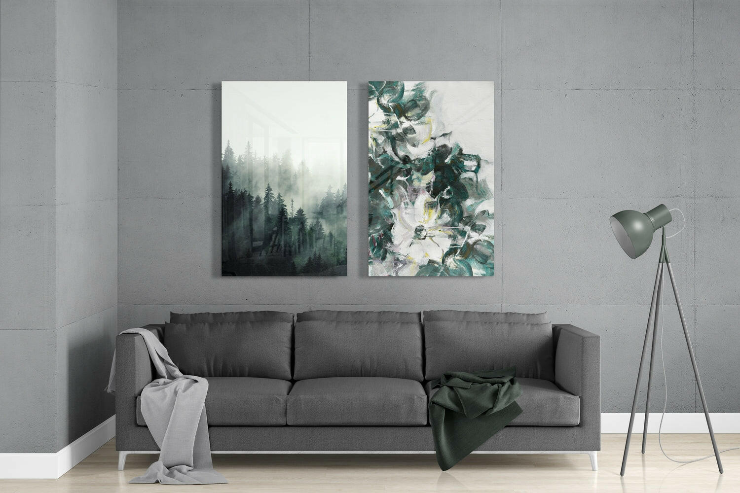 Modern living room interior with gray sofa displaying two glass wall art pieces: misty forest landscape and botanical floral design in green tones.