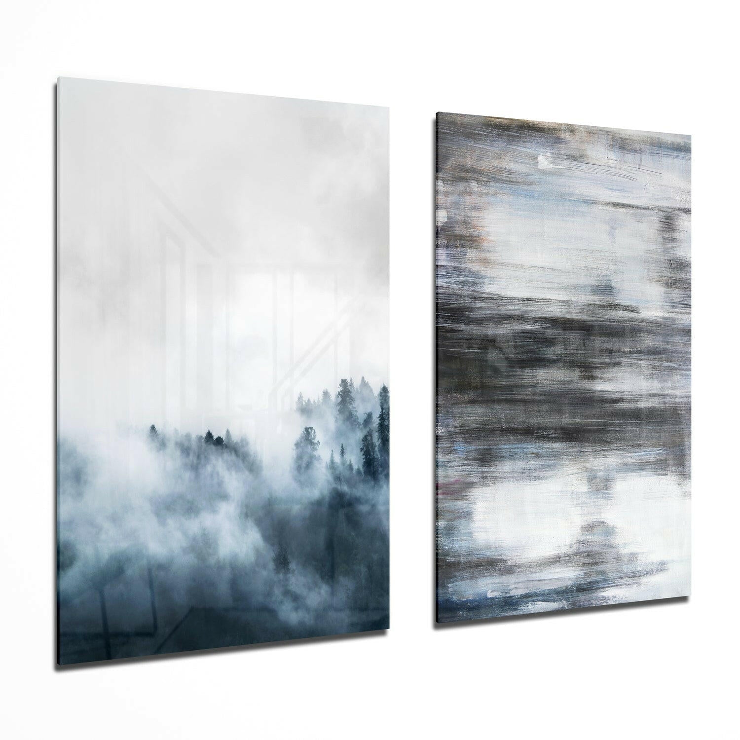 Two modern glass wall art panels displayed side by side: left panel shows misty forest trees in blue-gray tones; right panel features abstract horizontal brushstrokes in white, gray, and blue.