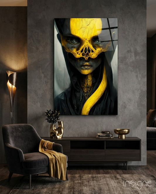 Glass art panel displaying a stylized face with yellow skull overlay and black features mounted on textured gray wall above dark furniture.