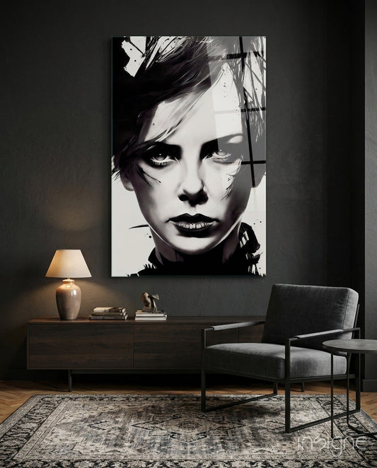 Black and white portrait glass art panel displayed above wooden console table in modern living room setting with chair and lamp.