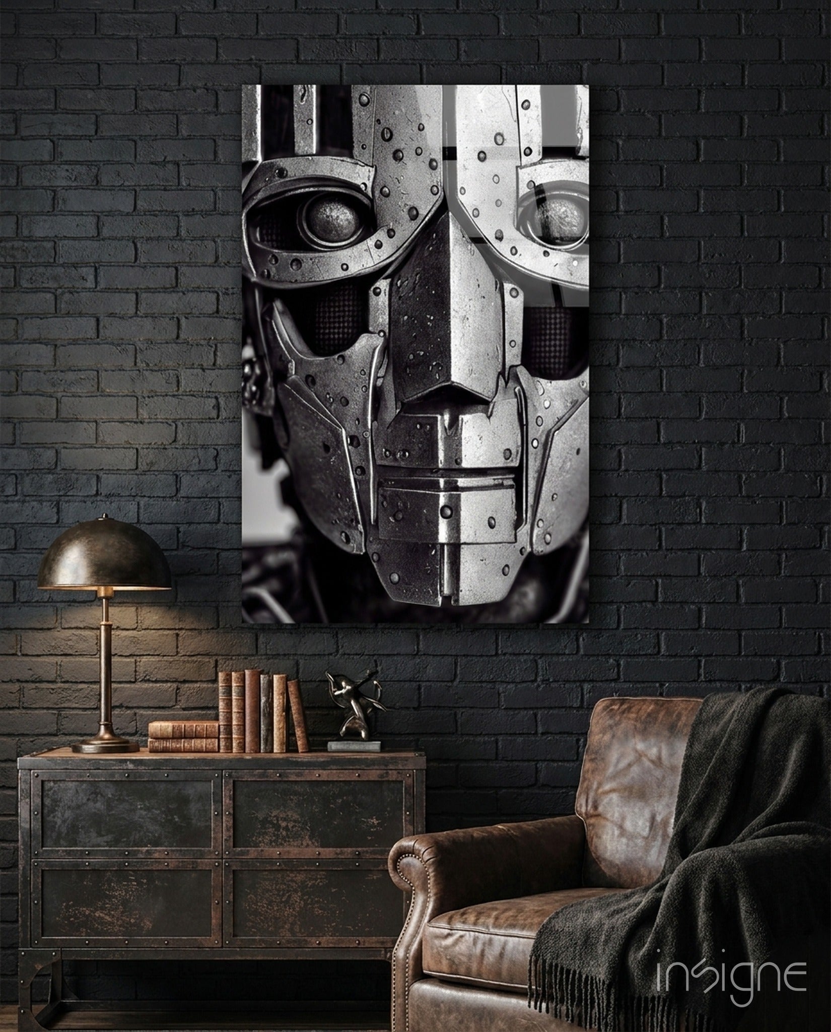 Black and white glass art panel depicting a segmented robotic face with riveted metal plating mounted on dark brick wall above industrial furniture.