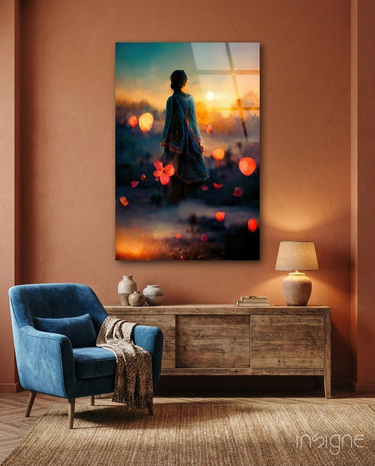 Glass wall art depicting a silhouetted figure viewing a sunset landscape with glowing bokeh lights, displayed above wooden furniture in a warm-toned room.