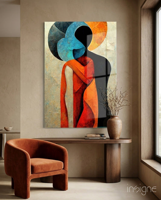 Abstract glass wall art depicting a stylized figure with blue circular head and red-orange draped fabric, displayed above wooden console table with terracotta chair.